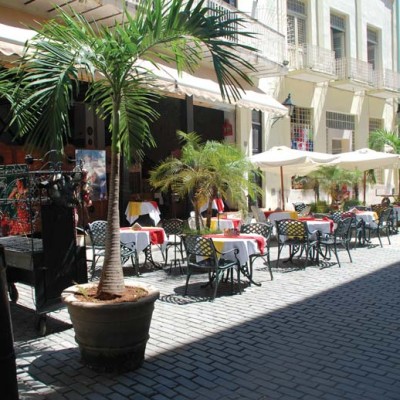 A sidewalk cafe at El Meson de la Flota near Plaza Vieja in Old Havana. The old cannons to the left in the photo are used to block vehicular access during certain hours and are commonly seen throughout Old Havana.