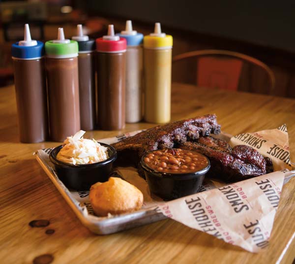 House-made rubs and a selection of sauces allow guests to experiment with the taste and heat factor for barbecue, ribs and brisket. Here, sides include baked beans, a cornbread muffin and cole slaw.